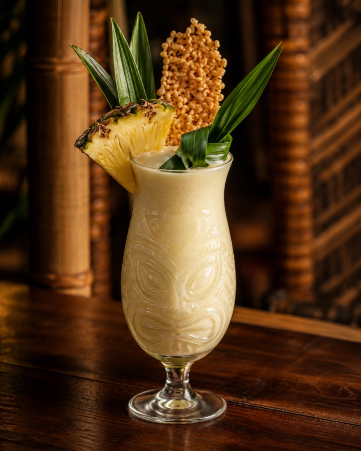 Khao Niew Colada in a hurricane glass with pineapple and toasted sticky rice